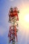 Telecoms tower with transmitter antenna on the bright blue sky and sun flare background