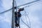 A telecoms worker is shown working from a utility pole ladder while wearing high visibility personal safety clothing, PPE, and a