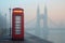 telephone booth on a foggy london morning with tower bridge behind