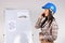 Telephone conversation. Woman architect wearing hard hat talking on phone against the background of working projects