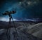 Telescope pointing the milky way in a rocky desert