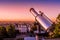Telescope with a rooftop view from Montmartre Hill during a vibrant and colorful sunrise, Paris, France.