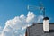 Television Aerial on a house roof with blue sky and clouds