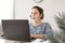 Teleworking woman with a headphones and a laptop computer at home in the livingroom. Telework concept and empty copy space