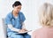 Tell me about your symptoms. Shot of a female nurse sitting with a clipboard while having a consultation with a patient.
