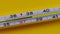 Temperature rising shown on a thermometer on a yellow background close-up.