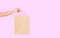 Template blank package. African american woman hand holding a paper kraft bag on pink background. Delivery and shopping