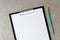 Template of white paper with simple pencil on light grey concrete background in a black tablet with a clip. Concept of