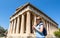 Temple of Hephaestus in Ancient Agora, Athens, Greece. Female person photographs the classical Greek building