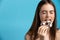 Temptation food. Pretty caucasian woman enjoy donut isolated over blue background