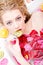 Tempting beautiful young blond woman in a bath with flower petals biting piece of kiwi closeup portrait