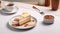 a tempting caramel Biscoff cheesecake displayed on a white table, accompanied by a slice and a cup of tea or coffee,the