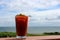 Tempting drink of bloody Mary mix and olives in chilled glass on railing by the water`s edge