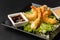 Tempura Deep Fried Shrimp Ebi with sweet chili and soy sauce on black board stone on dark background. Japanese food style
