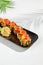 Tempura sushi roll with grapefruit and mango sauce. Hot maki sushi in black plate on white background. Summer menu for japanese