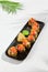 Tempura sushi roll with grapefruit and mango sauce. Hot maki sushi in black plate on white background. Summer menu for japanese