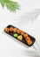 Tempura sushi roll with grapefruit and mango sauce. Hot maki sushi in black plate on white background. Summer menu for japanese