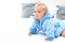 Ten month blond baby boy crawling on bed in blue bathrobe. Baby care concept, banner copy space