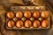 Ten organic rustic brown golden eggs shining glowing yellow orange in the light of the sunset in a cardboard on kraft paper