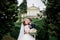 Tender brides pose between green trees in park