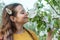 Tender brunette girl with natural makeup smelling blooming branch with closed eyes