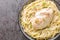 Tender chicken cooked in a creamy Italian flavored sauce and served on a bed of angel hair pasta closeup in the bowl. Horizontal