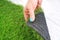 Tender female hand touching an artificial grass roll.