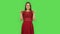 Tender girl in red dress is pointing up fingers. Green screen