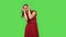 Tender girl in red dress is posing for camera making funny faces. Green screen