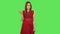 Tender girl in red dress is waving hand and showing gesture come here. Green screen