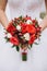 The tender hands of fiancee hold a wedding bouquet