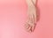 Tender hands with perfect nude manicure on trendy pastel pink background. Place for text