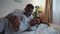 Tender moments. Zoom in portrait of young african american pregnant lady resting on bed with her husband, stroking belly