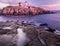 A tender morning with pink clouds on the coast of the Atlantic Ocean. lighthouse located on a rocky rock in the water.