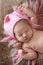 Tender newborn baby in pink cap sleeps stretching