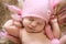 Tender newborn baby in pink cap sleeps stretching