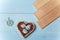 Tender pinwheel with bird and flowers, heart shaped box with decorated Easter eggs and brown boards on wooden blue background.