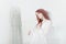Tender portrait of a young dreamy redhead woman in nightdress. She is sitting in dress room and planning to wear beautiful vintage