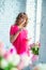 Tender pregnant girl in bright pink dress at the window