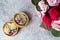 Tender romantic gift: sweet cakes with cream and berries and a bouquet of pink roses on a light background