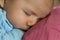 Tender scene: Cute peaceful baby boy sleeping in mothers arms.