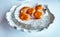 Tender slices of scallop covered with orange pike caviar on white mollusc shell in ice pieces