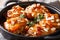 Tender sticky chicken thighs with apricot glaze and almond flakes close-up in a pan. horizontal