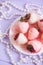 Tender strawberry set on white plate glazed in pink and white chocolate decorated with strips and pearl necklace on lilac backgrou