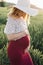 Tender and touching portrait of young pregnant woman. White hat emphasizes femininity and beauty. Pregnancy care. Beauty and
