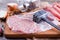 Tenderization of fresh pork steak on wooden chopping board