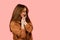 Tenderness and sensuality of a girl in a brown oversized suit on a pink background. Lifestyle. Cute and gentle young