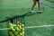 Tennis ball basket and feet of a girl training next to it