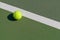 Tennis ball next to line on hard court