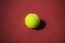 The tennis ball is placed on a red floor.